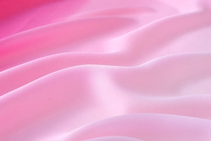 Makroaufnahme von rosa Seidenstoff mit sanftem Farbverlauf und eleganten Wellen