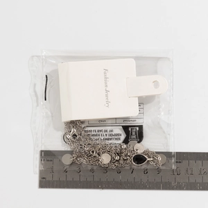 Macro shot of multi-layer silver necklace with black pendant and size scale ruler