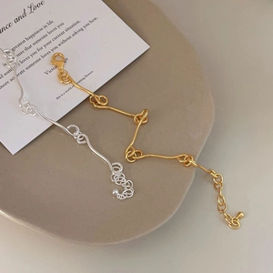 Detail of gold and silver interlocking wave link bracelets on a ceramic tray