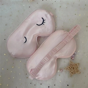 Detail of pink silk sleep mask featuring cartoon eyelash embroidery and elastic headband