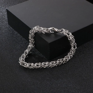 Macro detail of silver stainless steel basket weave chain with lobster clasp