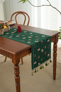 Close-up of Christmas table runner with festive Santa patterns and green tassels