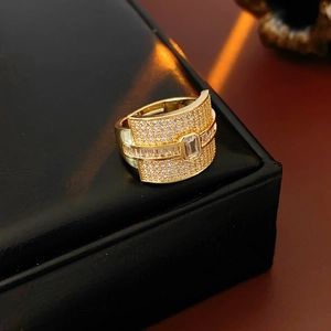 Close-up of golden wide band ring with square zircon and micro-pave setting on black box
