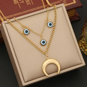 Gold double layer necklace featuring evil eye pendants and a crescent moon on a jewelry box