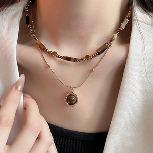 Detail of double-layer gold plated necklace with tiger eye beads on a female model