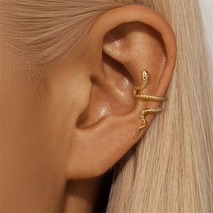 Close-up of a golden snake-shaped ear cuff on a female ear with detailed metallic texture