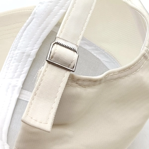 Detail of beige baseball cap featuring a premium metal slider buckle and twill fabric