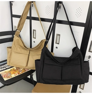 Detail of canvas tote bags in khaki and black with double flap pockets and adjustable straps
