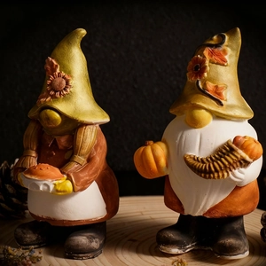 Detail of handcrafted fall gnome figurines holding pumpkin and pie on wood base
