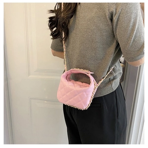 Detailed view of pink quilted mini bag with woven gold chain strap and stitching