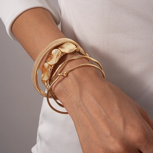 Detail of four-piece gold irregular geometric open bracelets on a model's wrist