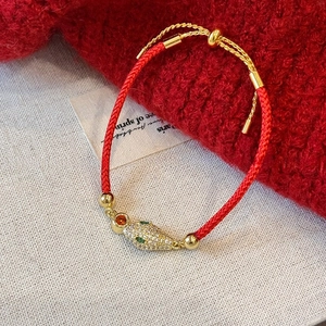 Vue détaillée du bracelet en corde rouge avec tête de serpent dorée et micro-diamants