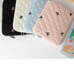 Close-up of quilted laptop sleeves in multiple colors with bow embroidery and zippers