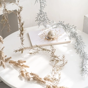Golden and silver Christmas tinsel vine decorations on a white table for festive atmosphere