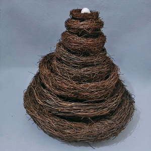 Close-up of stacked vine bird nests featuring a white decorative egg at the top
