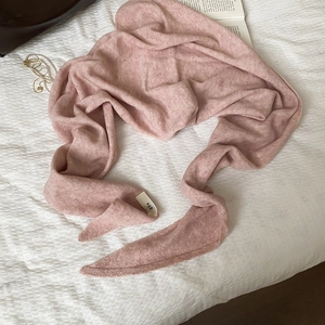 Detail eines rosa Strickschals mit weißem EGG-Markenetikett auf strukturiertem Stoff