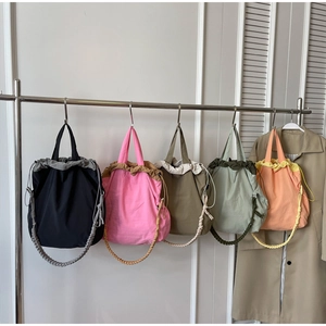 Dettaglio di borse a secchiello in nylon multicolore con manici intrecciati in posa