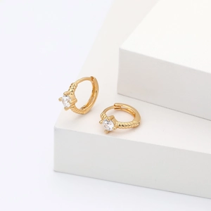 Macro shot of gold hoop earrings featuring ribbed texture and a clear cubic zirconia stone