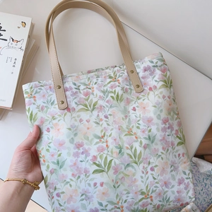 Close-up of floral cotton tote bag with premium leather straps and metal rivets