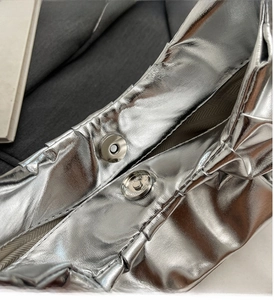 Detailed close-up of the silver metallic pleated bag with magnetic clasp and woven lining