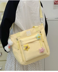 Detailed view of pale yellow nylon crossbody bag with cute star plush charms and star zipper