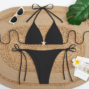 Two-piece black bikini with starfish gold buckle and tie sides on a summer beach mat