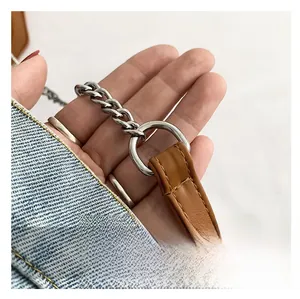 Detalle de la correa de hombro de cuero marrón con anillos de metal plateado y cadena