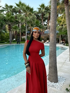 Detail of red one-shoulder pleated midi dress with floral headscarf and bracelets