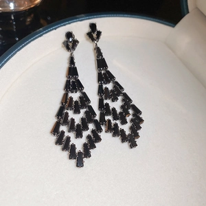 Close-up of black long tassel drop earrings with cubic zirconia in a white jewelry box