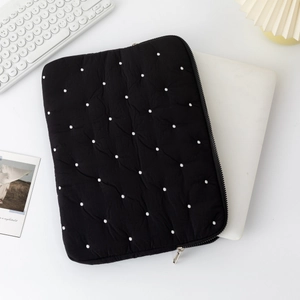 Close-up of black quilted laptop sleeve with white polka dots and silver metal zipper