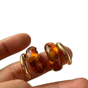 Retro C-shaped amber resin earrings with gold metal frame shown in hand closeup