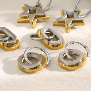 Detail view of 18K gold and silver star earrings on beige textured surface