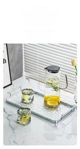 Detail of a luxury glass pitcher set with hammered texture cups on a metal handle tray
