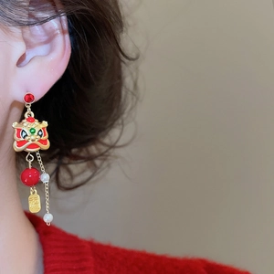 Macro shot of long lion dance earrings with red beads, pearls, and lucky Fu gold tag
