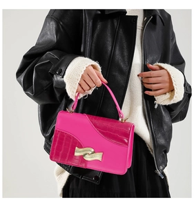 Detail of fuchsia patchwork handbag with golden wavy buckle and croc-embossed texture