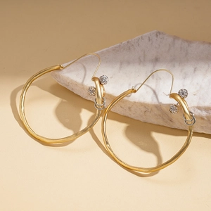 Vue détaillée des boucles d'oreilles créoles dorées avec billes sur support pierre