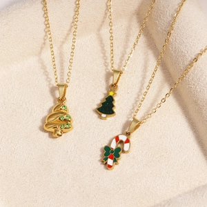 Detailansicht goldener Halsketten mit Weihnachtsbaum und Zuckerstange auf Stoffgrund