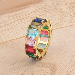 Macro shot of rainbow square-cut cubic zirconia ring with gold plating on wood