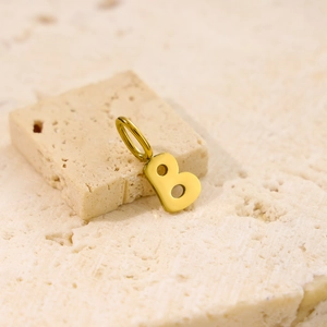 Macro shot of gold letter B pendant on textured stone for delicate stainless steel necklace