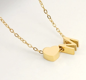 Vue détaillée du collier en acier doré avec pendentif lettre M et petit cœur