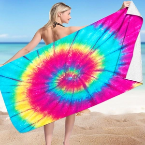 Detail of a large microfiber beach towel featuring a vibrant rainbow tie-dye design in use