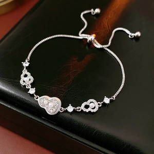 Close-up of silver-plated heart and gourd charm bracelet with pearls on leather box