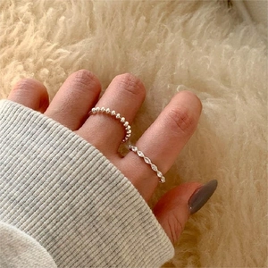 Close-up of 925 silver beaded ring and marquise zircon ring worn on a knit sleeve background