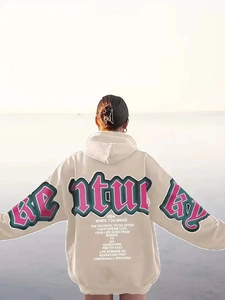 Outdoor view of oversized beige hoodie with vintage green and pink back letter print