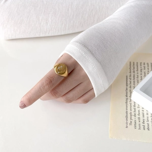 Detail of a gold signet ring with a sunburst pattern and inlaid white zircon crystals