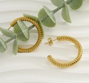 Macro detail of large gold twisted rope hoop earrings with 18k textured finish
