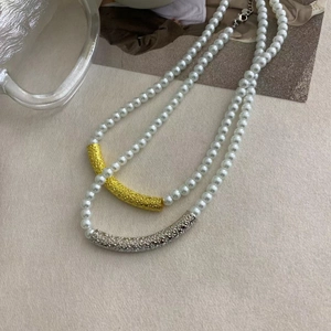 Detail of French style pearl necklaces with textured gold and silver curved metal tubes