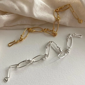 Detailed macro of gold and silver S925 sterling silver bold chain bracelets on fabric
