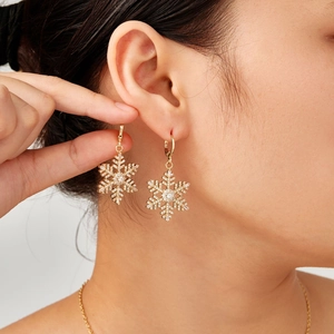 Golden snowflake drop earrings with micro-inlaid cubic zirconia worn by a model