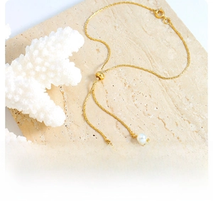 Detail of adjustable gold pearl necklace with slider clasp on natural stone background
